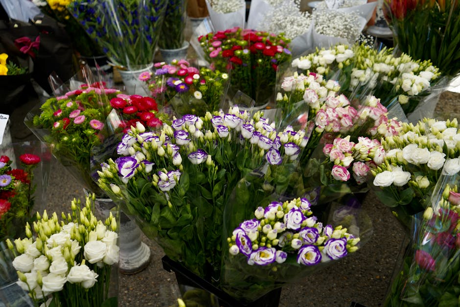 A variety of fresh flower bouquets displayed on a table at Docklands Flowers shop in West India Quay, featuring an assortment of blossoms including purple and white irises, white roses, and pink and r